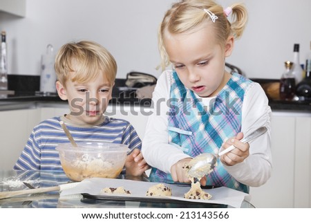 Happy brother and sister baking cookies in kitchen