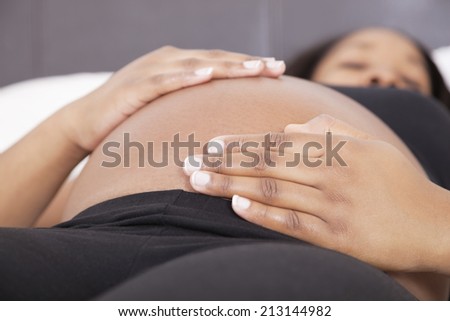 Young pregnant woman relaxing with hands on stomach