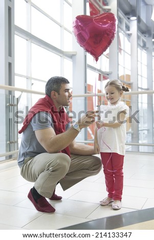 Father gives young daughter heart shaped balloon