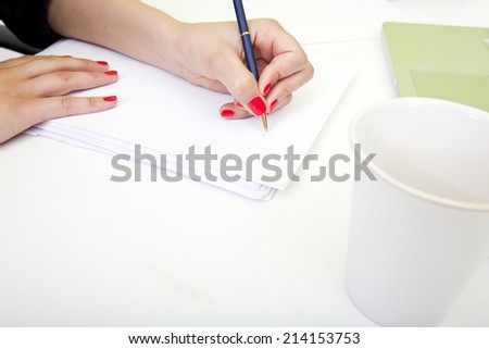 Close up of womans hands writing on paper.