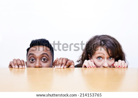 Work colleagues peeking over edge of table