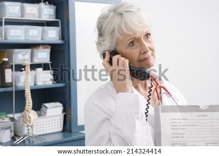 Senior medical practitioner stands on phone at medical cabinet