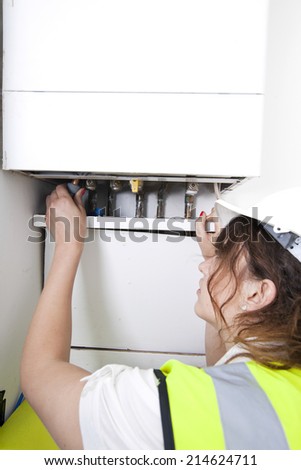 Female plumber servicing central heating boiler