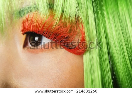 Extreme close-up of young woman\'s face with false eyelashes and green wig