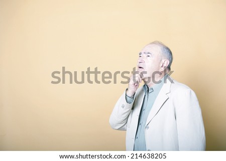 Senior adult man with his hand on his chin looking up inquisitively