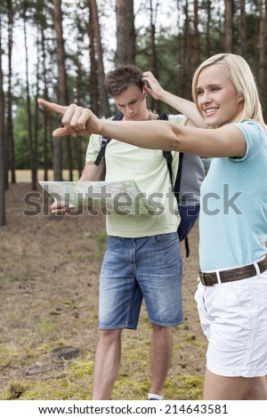 Young woman pointing away with confused man holding map in forest