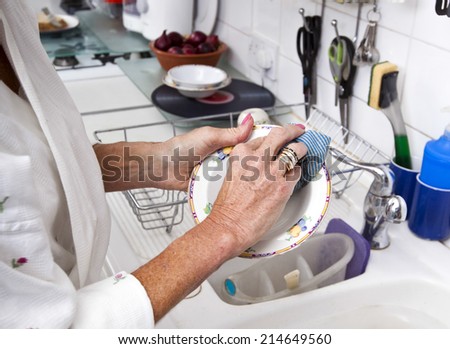 Cropped image of senior woman cleaning plate in kitchen