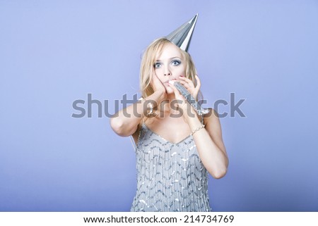 Sexy blonde party girl wearing silver dress and blowing party whistle