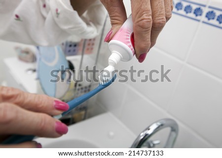 Cropped image of senior woman putting tooth paste on brush at home