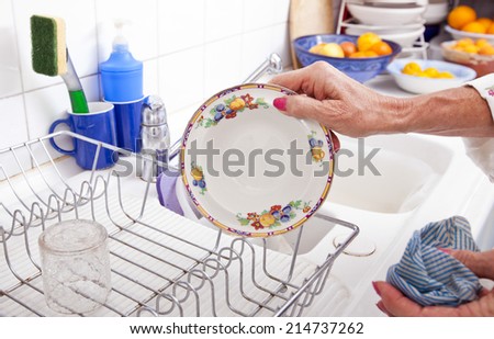 Cropped image of senior woman arranging plate in rack at kitchen counter
