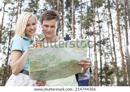 Young hiking couple reading map in forest