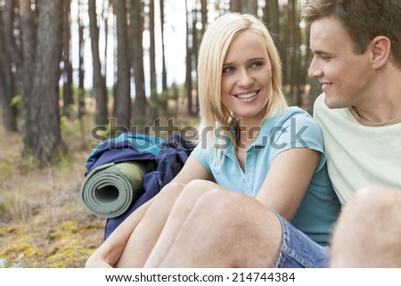 Hiking couple looking at each other while relaxing in forest