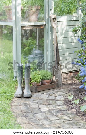 Garden tools and wellington boots outside shed