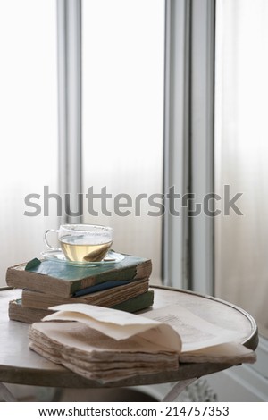 Open book on table with herbal tea in bedroom