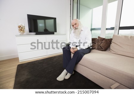Sad senior man sitting on sofa in living room