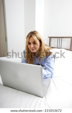 Businesswoman using laptop while lying in bed
