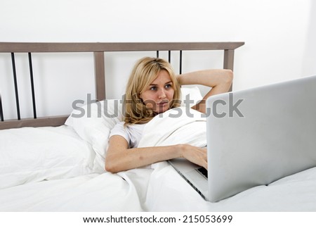 Young woman looking at laptop in bed