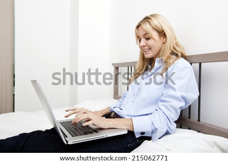 Smiling businesswoman using laptop in bed