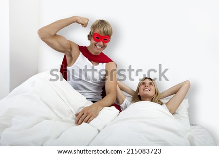 Portrait of man in superhero costume with woman on bed