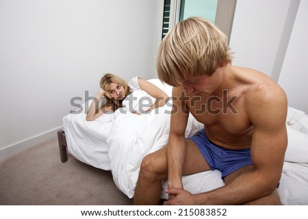 Sad man and woman on bed in house
