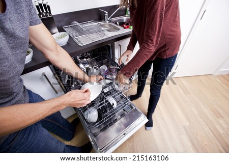 Caucasian couple loading dishwasher together in kitchen