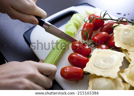 Woman\'s hand chopping cucumber at kitchen counter