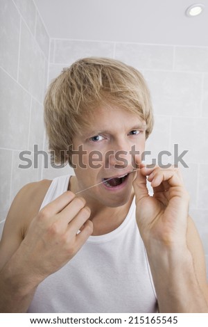 Portrait of man flossing teeth in bathroom