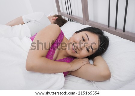 Thoughtful woman smiling while man sleeping in bed