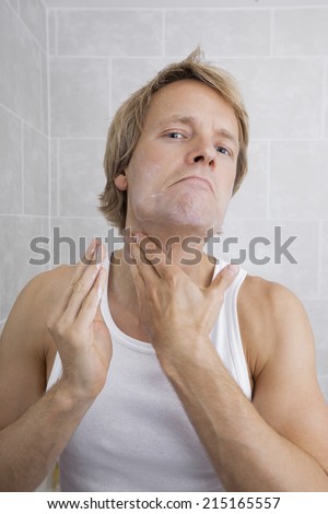 Portrait of mid-adult man applying aftershave moisturizer in bathroom