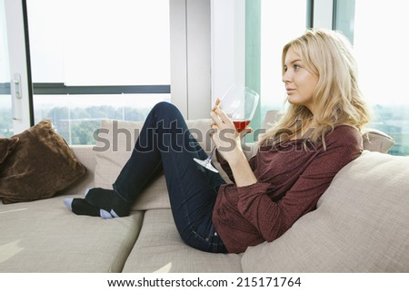 Side view of young woman with wine glass in living room at home
