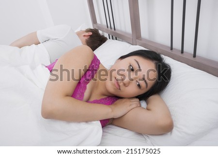 Displeased woman with man sleeping in bed