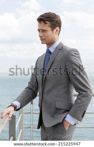 Thoughtful businessman with hand in pocket standing by terrace railings