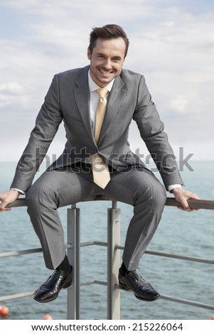 Full-length portrait of happy businessman sitting on terrace railings