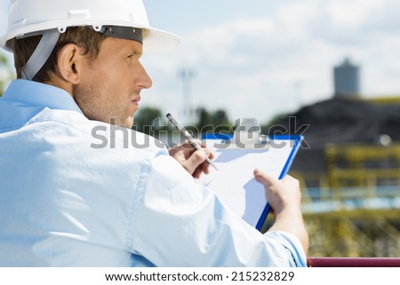 Back view of male architect with clipboard at construction site