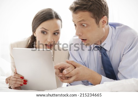 Shocked business couple using digital tablet in hotel