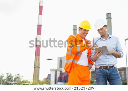 Two construction workers discussing over tablet PC at industry