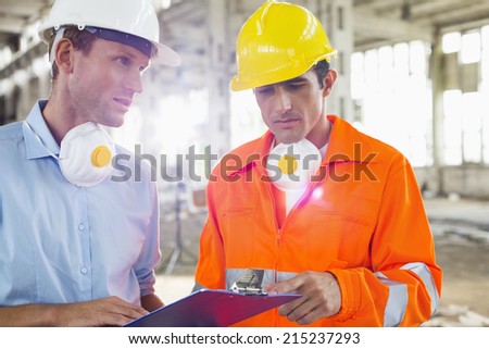 Male architects in protective workwear discussing at construction site