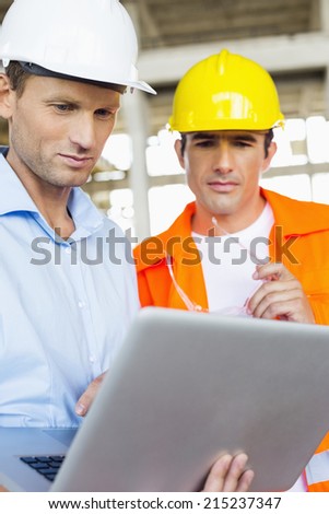 Male architects working on laptop at construction site