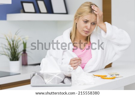 Young woman suffering from cold in kitchen