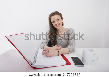 Portrait of smiling businesswoman writing notes at desk in office