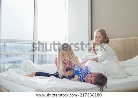 Happy parents looking at playful children in bedroom