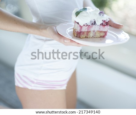 Mid section of woman with tasty raspberry cake in house