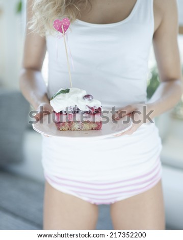 Mid section of woman with raspberry cake in house