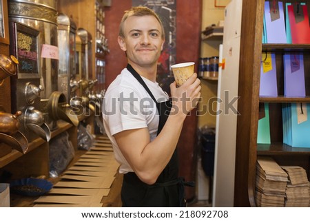 Portrait of male salesperson holding disposable coffee cup in store