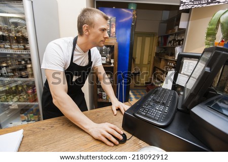 Portrait of salesman using computer at cash counter in supermarket