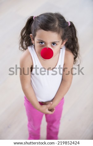 Portrait of cute little girl wearing clown nose at home