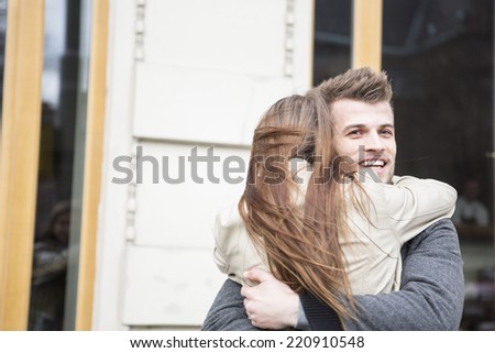 Happy young man hugging woman outside cafe