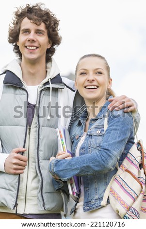 Happy young college students standing arm around at campus