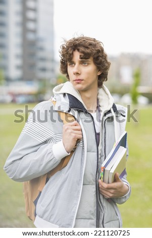 Young male university student holding textbooks at campus