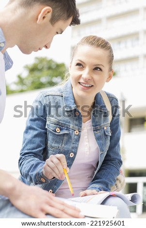 Young woman with male friend studying together at college campus